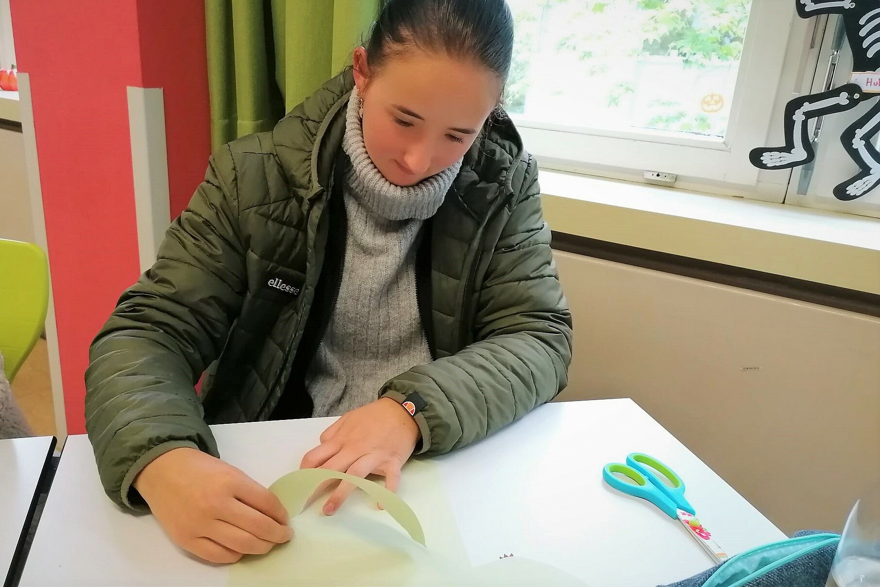 Eine Schülerin reißt frei Hand ein Blatt Papier zu einer Birne