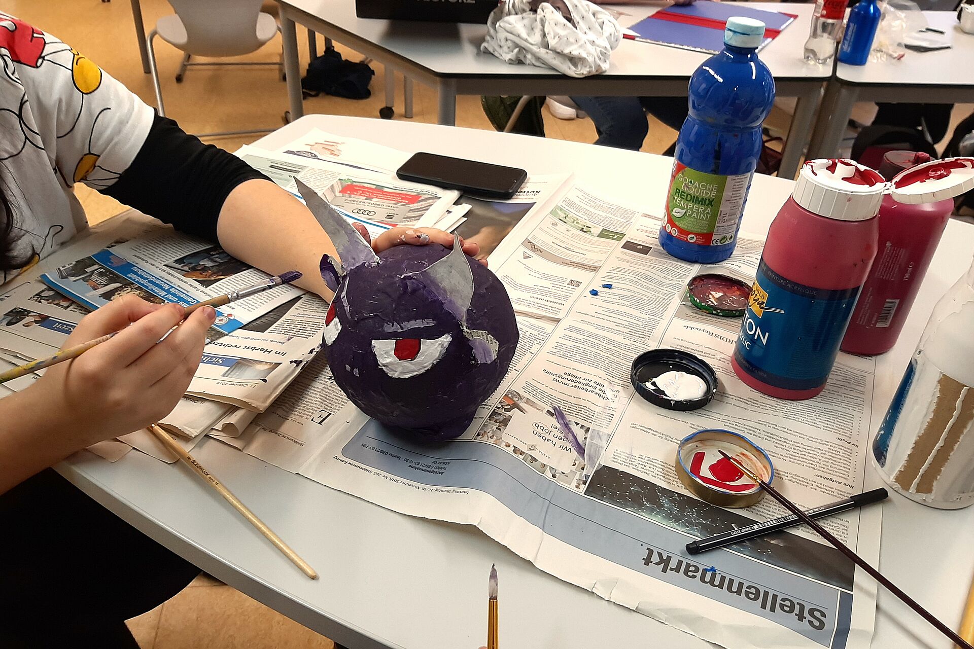 Schülerin arbeitet mit Pappmaschee im Unterricht und fertigt eine Figur an