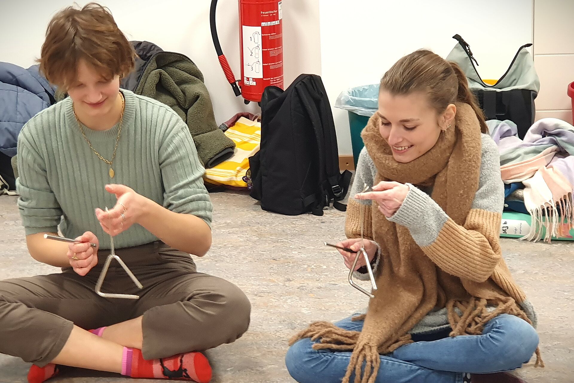 Zwei Schülerinnen spielen eine Triangel im Gleichklang