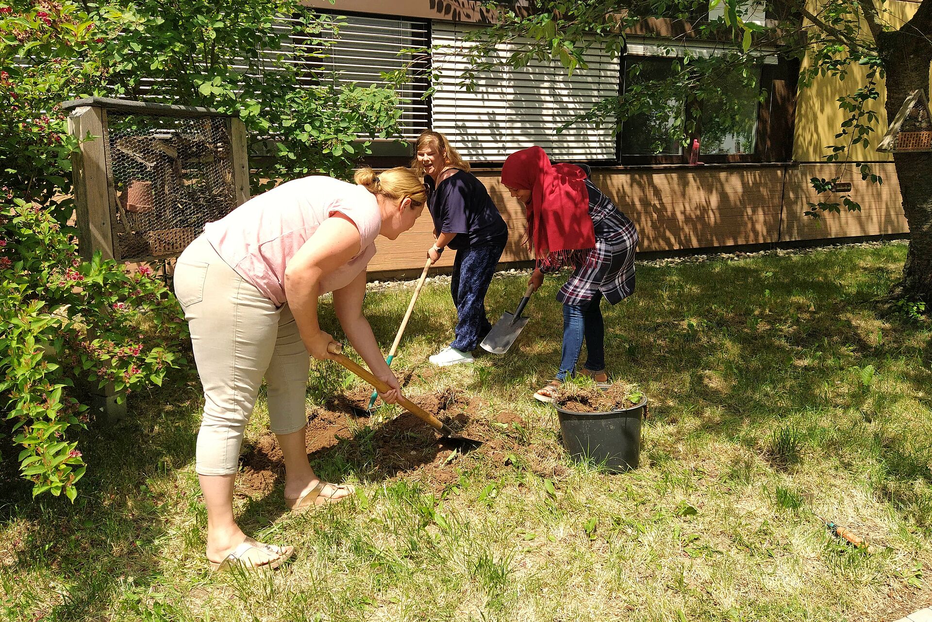 Zwei Schülerinnen bei der Bearbeitung des Bodens mit Gartenhacken