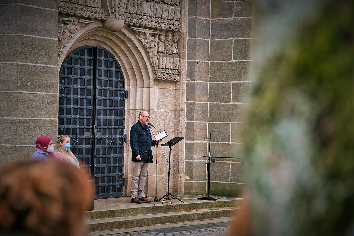 Ein Redner vor einer Kirchentür